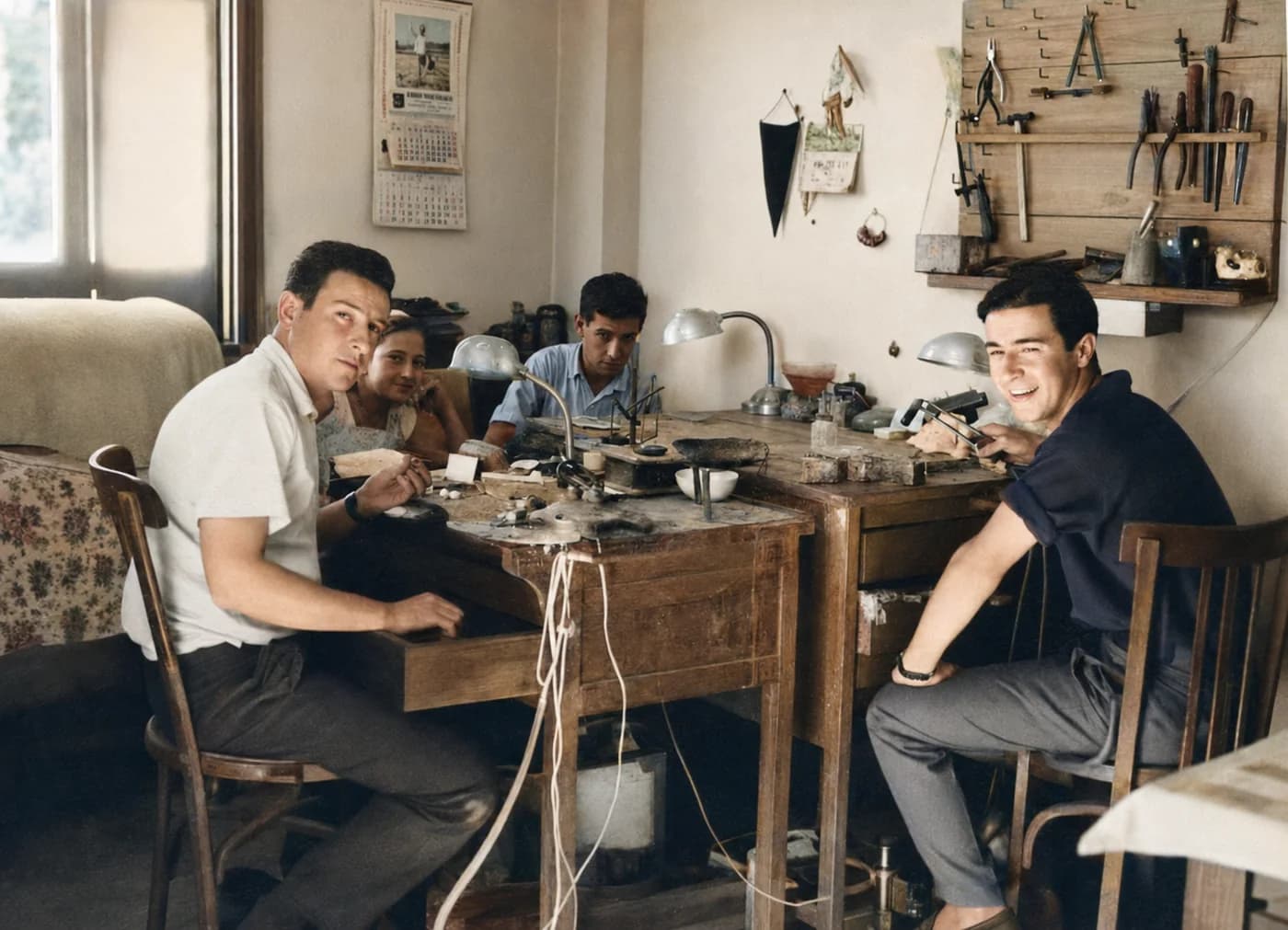 Fotografía familiar restaurada y coloreada de cuatro personas alrededor de los bancos del antiguo taller
