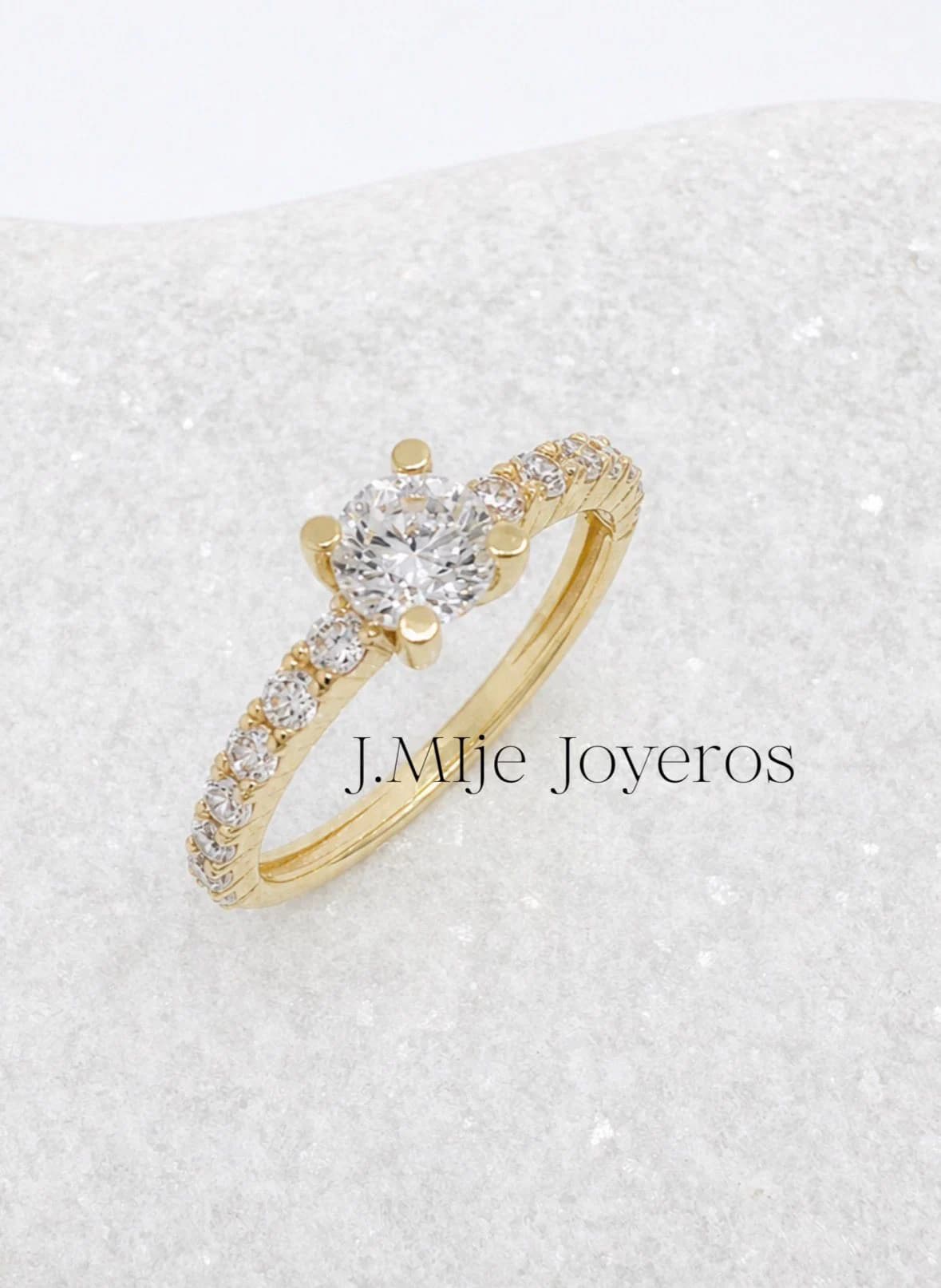 Anillo dorado con piedra central y detalles brillantes